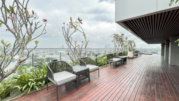 A rooftop terrace with outdoor furniture, potted plants, and a city view. - Comfy Studio For 2 Pax At B Residence Grogol (Jakarta)