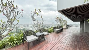 Een terras op het dak met buitenmeubilair, plantenbakken en uitzicht over de stad.