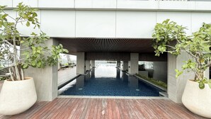 A modern indoor pool with a wooden deck, surrounded by large planters with green foliage. - Comfy Studio For 2 Pax At B Residence Grogol (Jakarta)