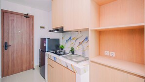 A kitchen with wooden cabinets, a stainless steel sink, a stove, and a small potted plant. - Comfy Studio For 2 Pax At B Residence Grogol (Jakarta)