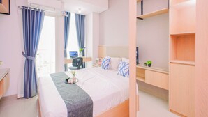 A hotel room with a bed, a desk, a chair, a TV, and a wardrobe. - Comfy Studio For 2 Pax At B Residence Grogol (Jakarta)