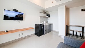 A modern kitchen with a refrigerator, microwave, and a flat-screen TV mounted on the wall. - Restful 1Br For 2 Pax With City View At Cisauk Point Apartment (Pagedangan)