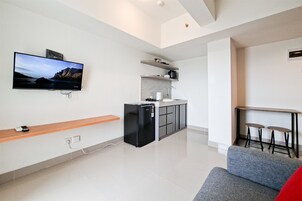 A modern kitchen with a refrigerator, microwave, and a flat-screen TV mounted on the wall.