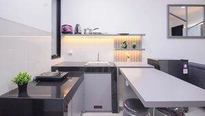 A modern kitchen with a built-in dishwasher, a coffee machine, and a small refrigerator. - Homey And Modern 2Br At Apartment Green Royal Condo House (Jakarta)