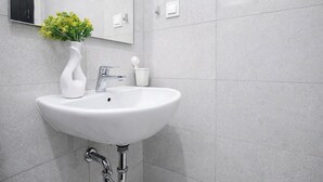 A bathroom with a white sink, chrome faucet, and a mirror above it. - Homey And Modern 2Br At Apartment Green Royal Condo House (Jakarta)