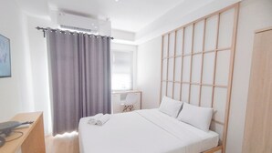 A hotel room with a bed, a desk, a chair, and a window with curtains. - Japanese Style Studio At Kyo Society Apartment (Surabaya)