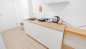 A compact kitchen with a sink, a coffee maker, and a kettle on the countertop. - Japanese Style Studio At Kyo Society Apartment (Surabaya)