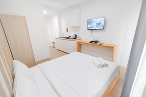 Ein Hotelzimmer mit einem Bett, einem Schreibtisch mit Flachbildfernseher, einer Kaffeemaschine und einem Holzschrank.