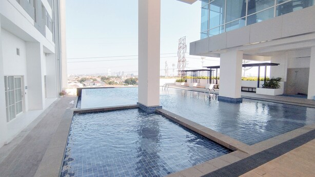 An indoor swimming pool with clear views of the cityscape, modern architecture, and a covered seating area. - Japanese Style Studio At Kyo Society Apartment (Surabaya)