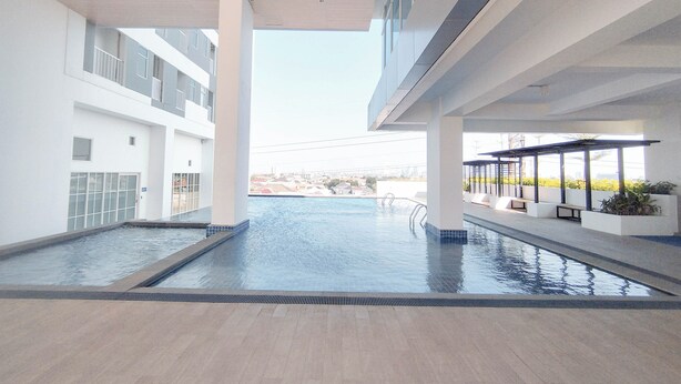 En modern inomhuspool med fri utsikt över de omgivande byggnaderna och en klar himmel.