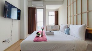 Ein Hotelzimmer mit Bett, Wandfernseher, Klimaanlage und einem fenster mit Vorhängen.
