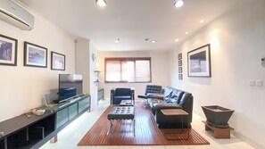Ein modernes Wohnzimmer mit Flachbildfernseher, Ledersofa und Couchtisch aus Holz.