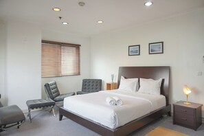 Ein Hotelzimmer mit einem großen Bett, einem Schreibtisch, einem Stuhl und einem Nachttisch mit Lampe.