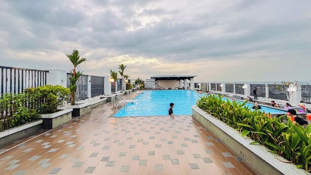 A rooftop swimming pool with a view of the city skyline, surrounded by a fence and potted plants. - Functional And Cozy Studio At Skyview Medan Apartment (Medan)