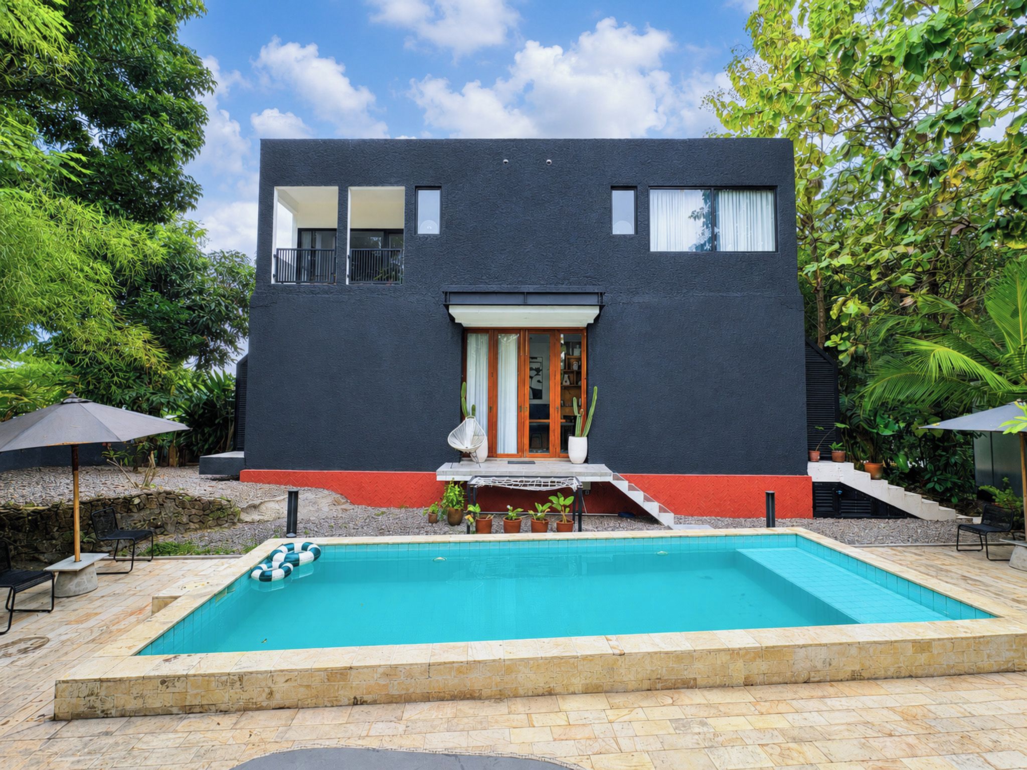 A modern two-story house with a swimming pool, surrounded by greenery.