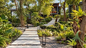 A pathway leading to a modern building with a stone staircase and lush greenery. - Guru Giri Forest Cabin Villa 2BR with Pool Access (Srimulyo)