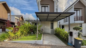 A modern residential building with a covered entrance, a stone facade, and a well-maintained garden. - Damara 2BR Villa Jimbaran Near GWK (Jimbaran)