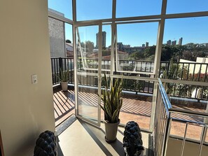 A balcony with a view of a cityscape, a potted plant, and a decorative sculpture. - Ravello Residential AP08 Foz do Iguaçu (Foz do Iguaçu)