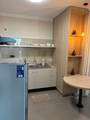 A modern kitchen with a built-in refrigerator, a sink, and a round dining table. - Ravello Residential AP08 Foz do Iguaçu (Foz do Iguaçu)