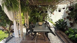 A covered patio area with a table and chairs, surrounded by potted plants and a tiled floor. - Ravello Residential AP08 Foz do Iguaçu (Foz do Iguaçu)