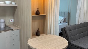 A modern room with a round table, a sofa, a kitchen area with cabinets, and a bed with curtains. - Ravello Residential AP08 Foz do Iguaçu (Foz do Iguaçu)