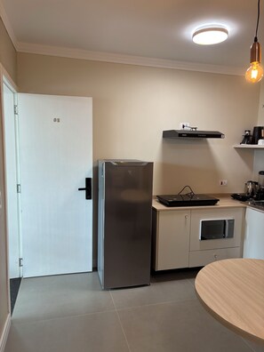 A modern kitchen with a stainless steel refrigerator, a built-in oven, a microwave, and a coffee maker on the countertop. - Ravello Residential AP08 Foz do Iguaçu (Foz do Iguaçu)