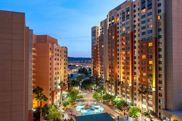 A high-rise hotel with multiple floors, a central courtyard with a pool, and surrounding greenery.