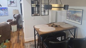 En matplats med ett träbord, svarta stolar och en hängande lampa.