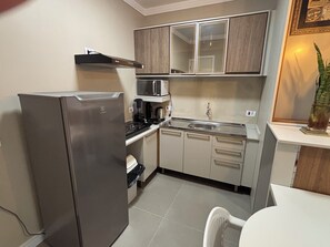 Uma cozinha compacta com geladeira, micro-ondas, fogão, pia e armários.
