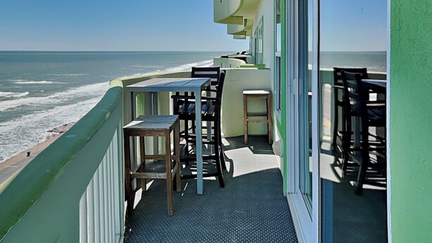 A balcony with a view of the ocean, featuring a table and chairs. - Ocean Grove 1003 - Pelican Sky (Galveston)