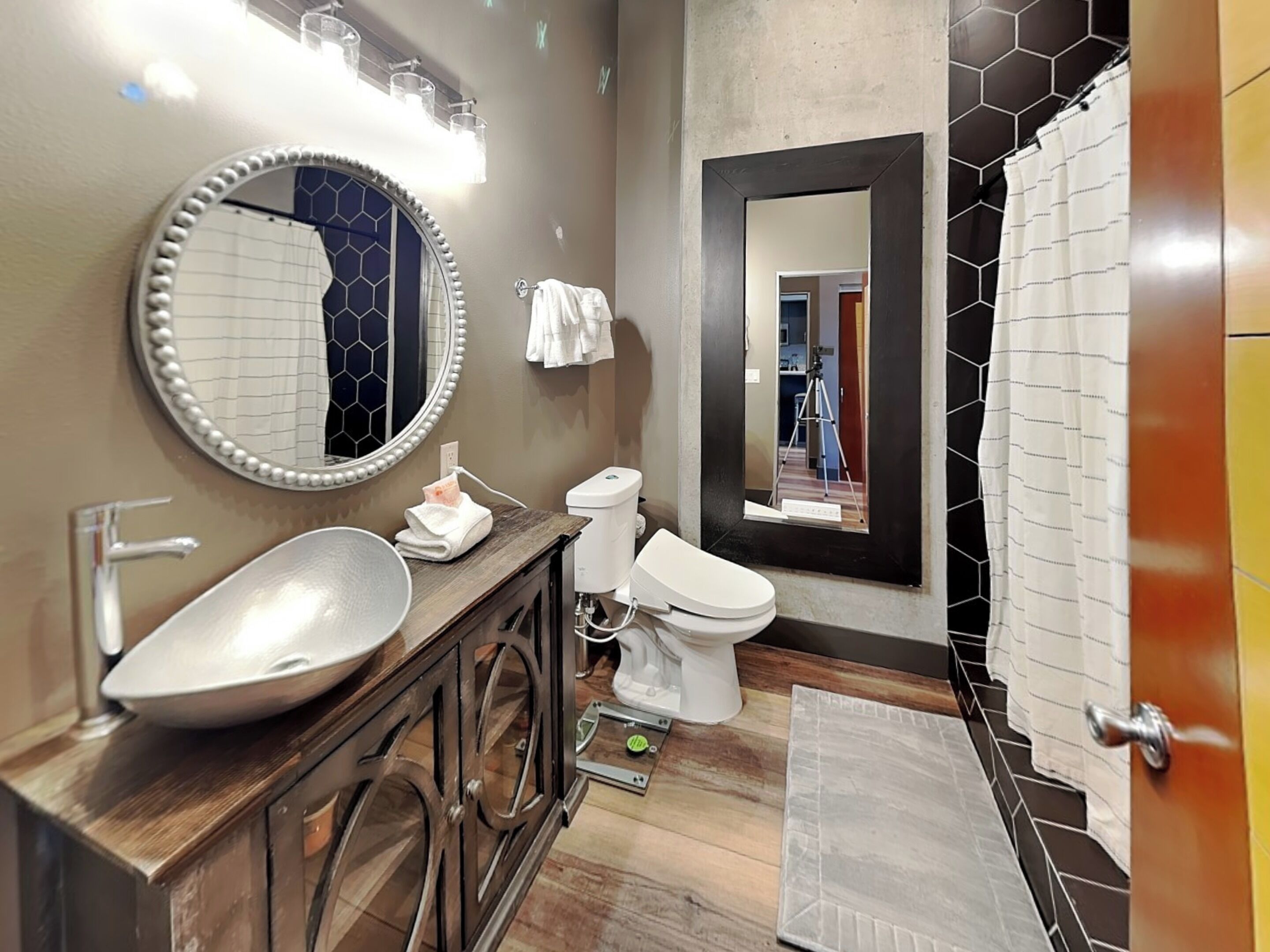 Un baño moderno con tocador, lavamanos, espejo, inodoro y ducha.