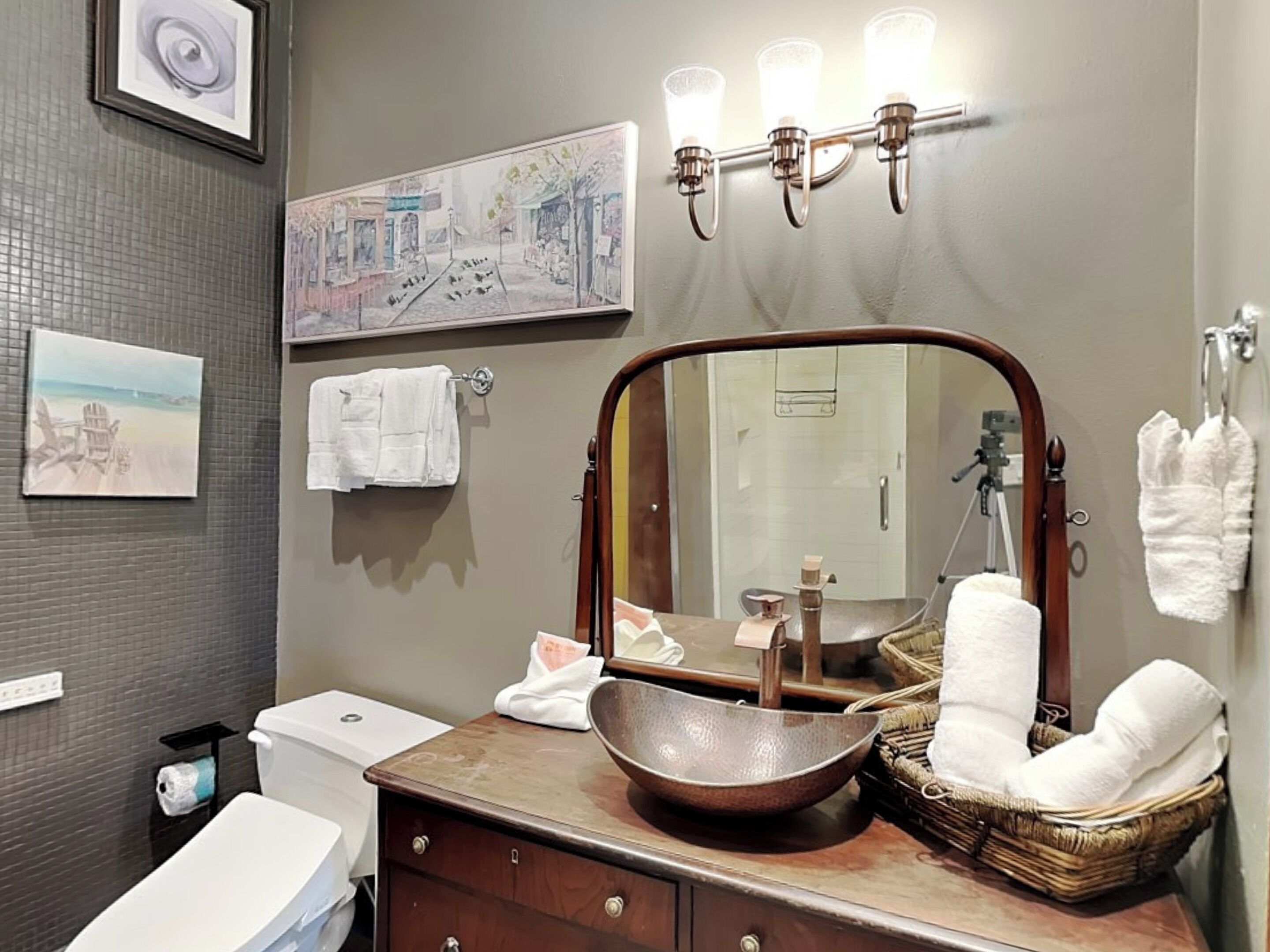 A bathroom with a large mirror, a sink with a bowl, a toilet, and a towel rack.