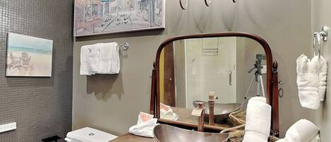 A bathroom with a large mirror, a sink with a bowl, a toilet, and a towel rack.