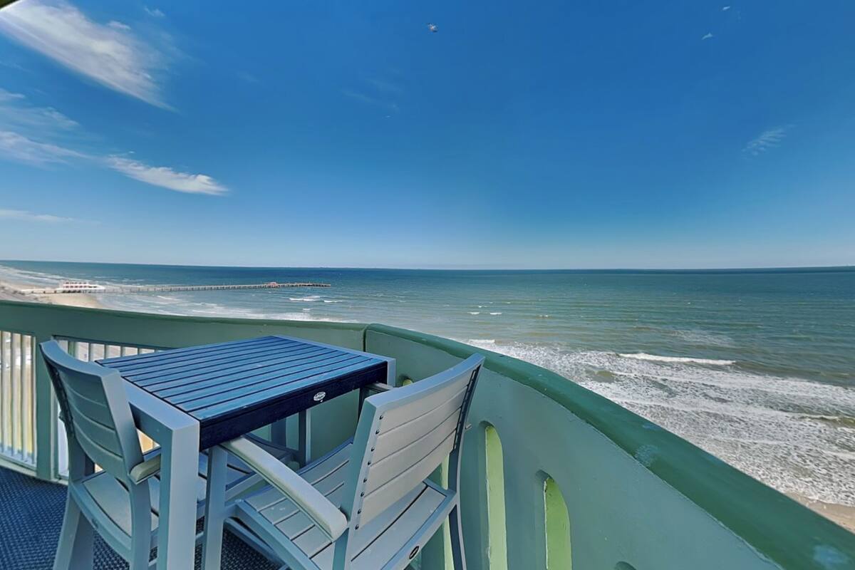 A balcony with a table and chairs overlooking the ocean.
