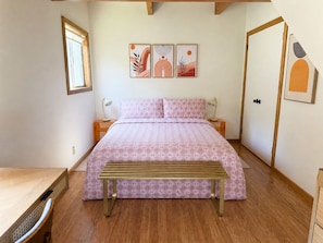 Ein Schlafzimmer mit einem Bett, Nachttischen, einer Bank und Kunstwerken an der Wand.