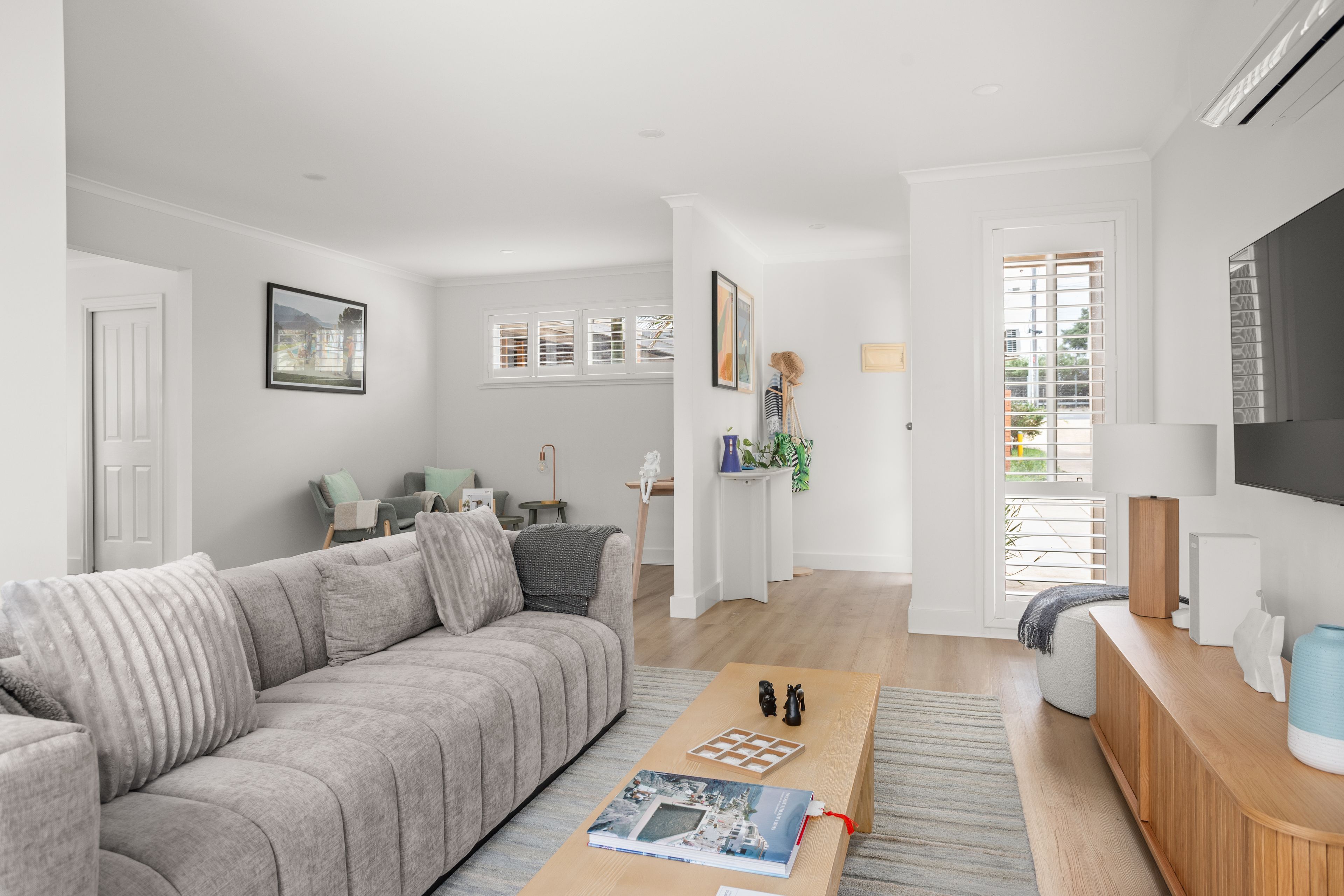A modern living room with a grey sofa, a coffee table with a magazine, a TV, and a wooden side table.