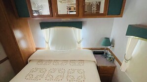 Una cama con bordados florales, una mesita de noche con lámpara y un espejo sobre la cama.