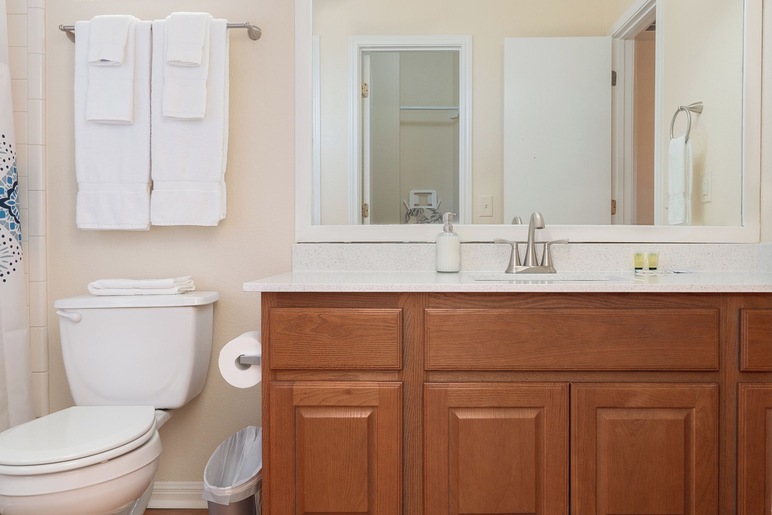 Une salle de bain équipée de toilettes, de meubles en bois, d’un miroir et d’un porte-serviettes.