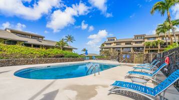 A swimming pool with lounge chairs, a lifebuoy, and a stone wall.