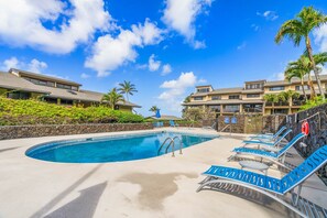 A swimming pool with lounge chairs, a lifebuoy, and a stone wall. - 1308 Oceanview | Turtles•Pool•Spa•Whales (Poipu)