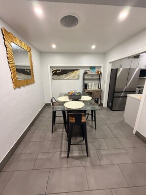 A modern kitchen with a dining area, featuring a large refrigerator, a microwave, and a coffee maker. - Fabulous comfortable house in the heart of Miami. (Miami)