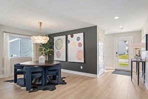 A modern dining area with a round table, chairs, and a hanging light fixture. - Private Pool, Infared Sauna, Full Gym, Hot Tub, Sleeps 16 (Grandville)