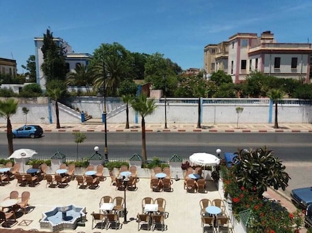 An outdoor cafe with tables and chairs, a street in the background, and buildings.. HOTEL CHOUMISSE