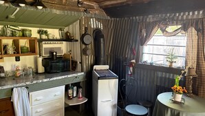 Une cuisine compacte équipée d’un réfrigérateur, d’un four à micro-ondes et d’une cuisinière. Un petit coin repas avec une table et des chaises est également disponible.