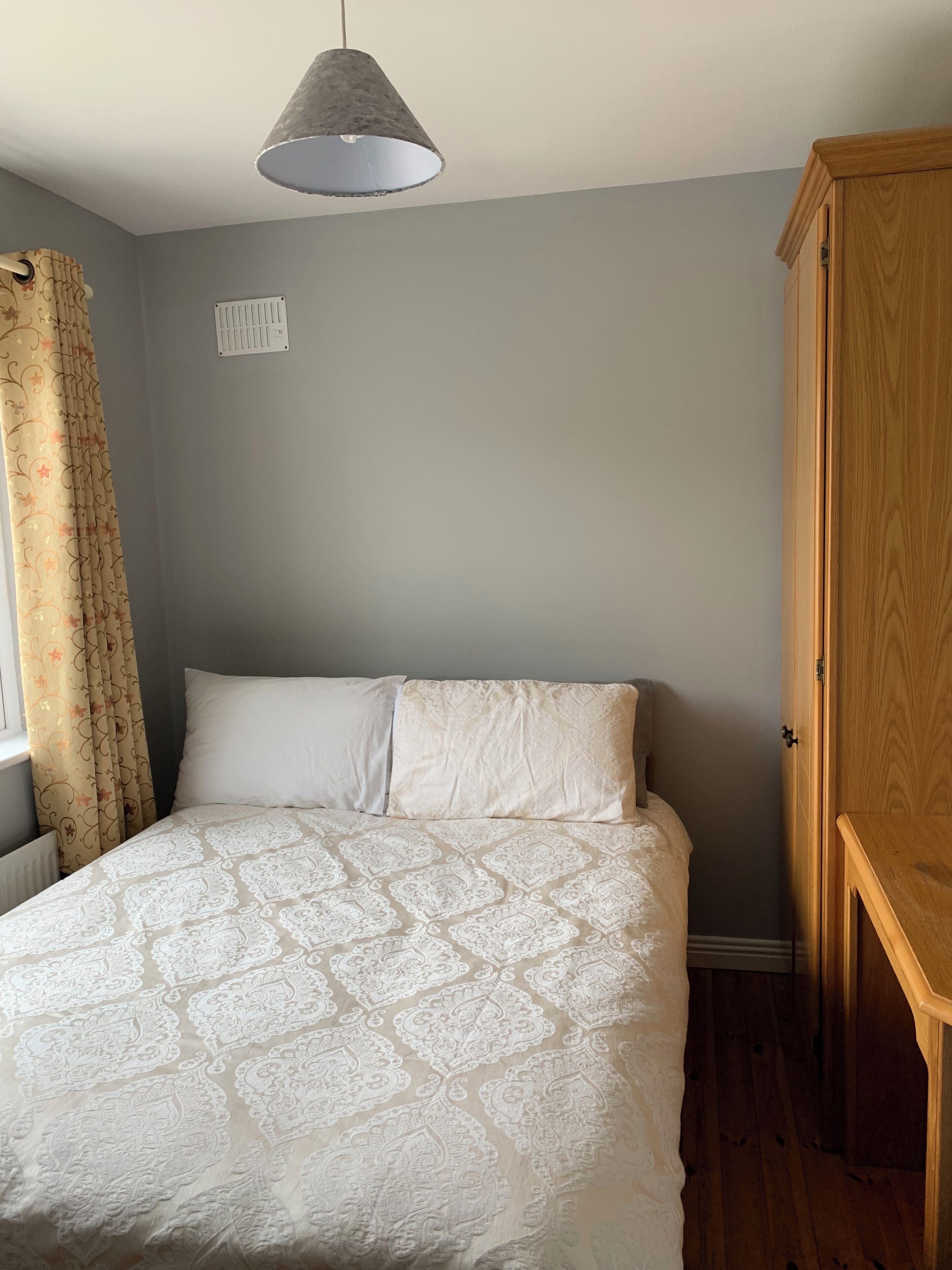 Un dormitorio con cama, un armario de madera, un radiador y una lámpara colgante.