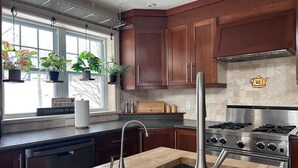 Een moderne keuken met houten kastjes, een RVS spoelbak en een gasfornuis.
