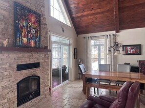 A spacious room with a fireplace, a dining area, and a large window.