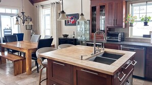 Een keuken met een houten kookeiland, een eethoek met een houten tafel en uitzicht op de omgeving.