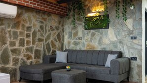 A modern living room with a sectional sofa, a patterned rug, and a stone wall with greenery.