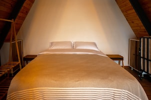 Un dormitorio con una cama grande, vigas de madera y una escalera.